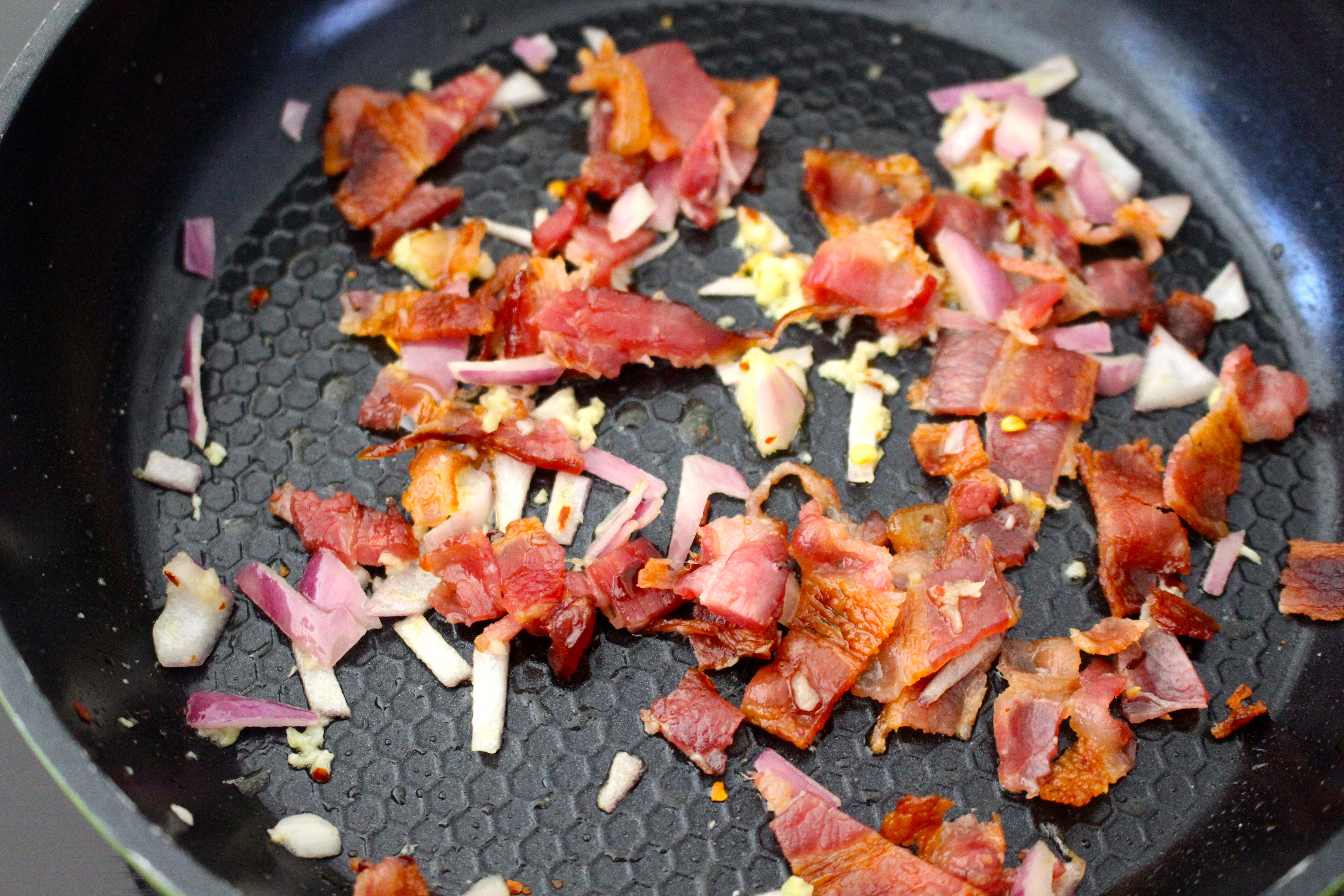 Bacon cooking with red onion and garlic